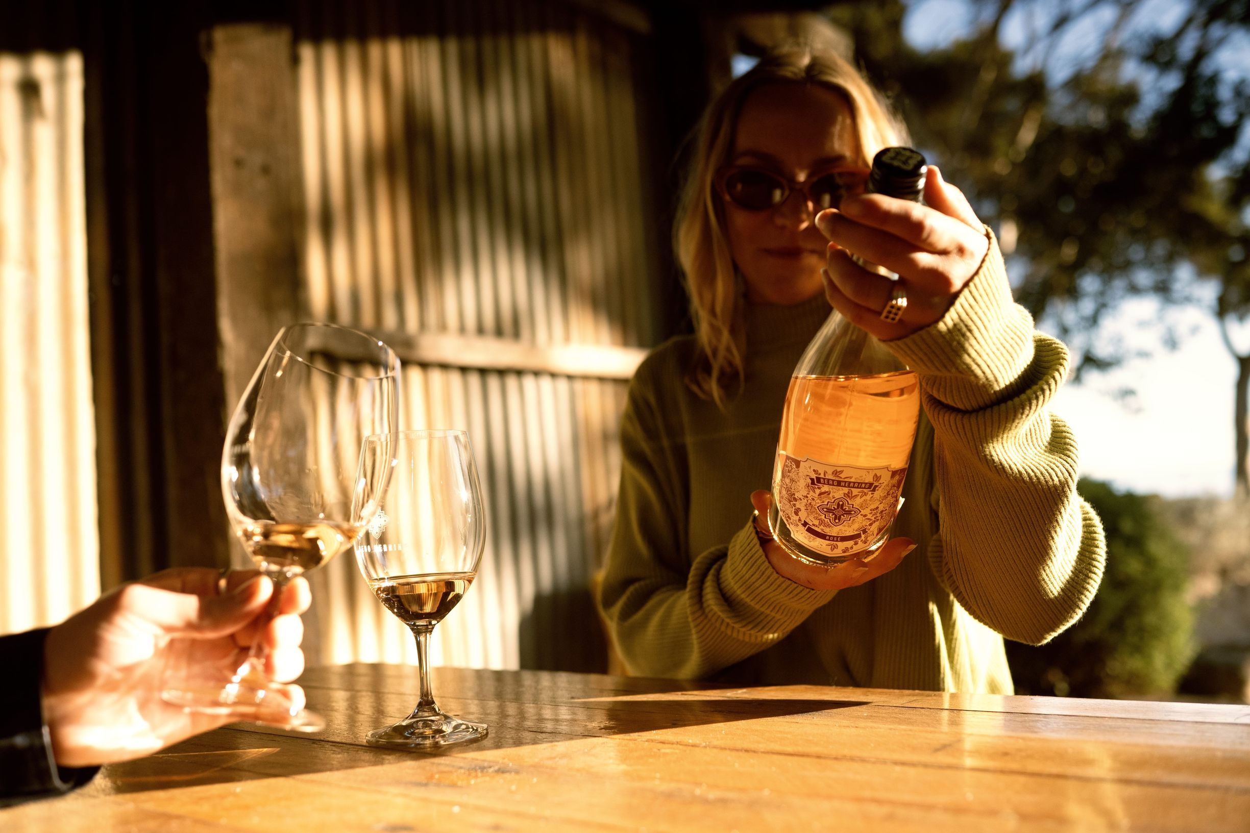 A couple enjoying a glass of wine and the girl is holding the bottle in front of her face
