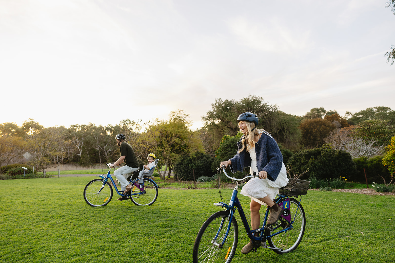 A male and a female riding an ebike with a child in a basket on the back in McLaren Vale