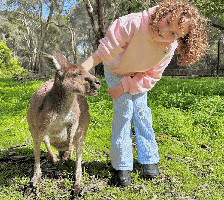 Young girl in pink jumper and blue jeans patting a knagaroo at Woodstock Wines Kangaroo Sanctuary Feeding Experience