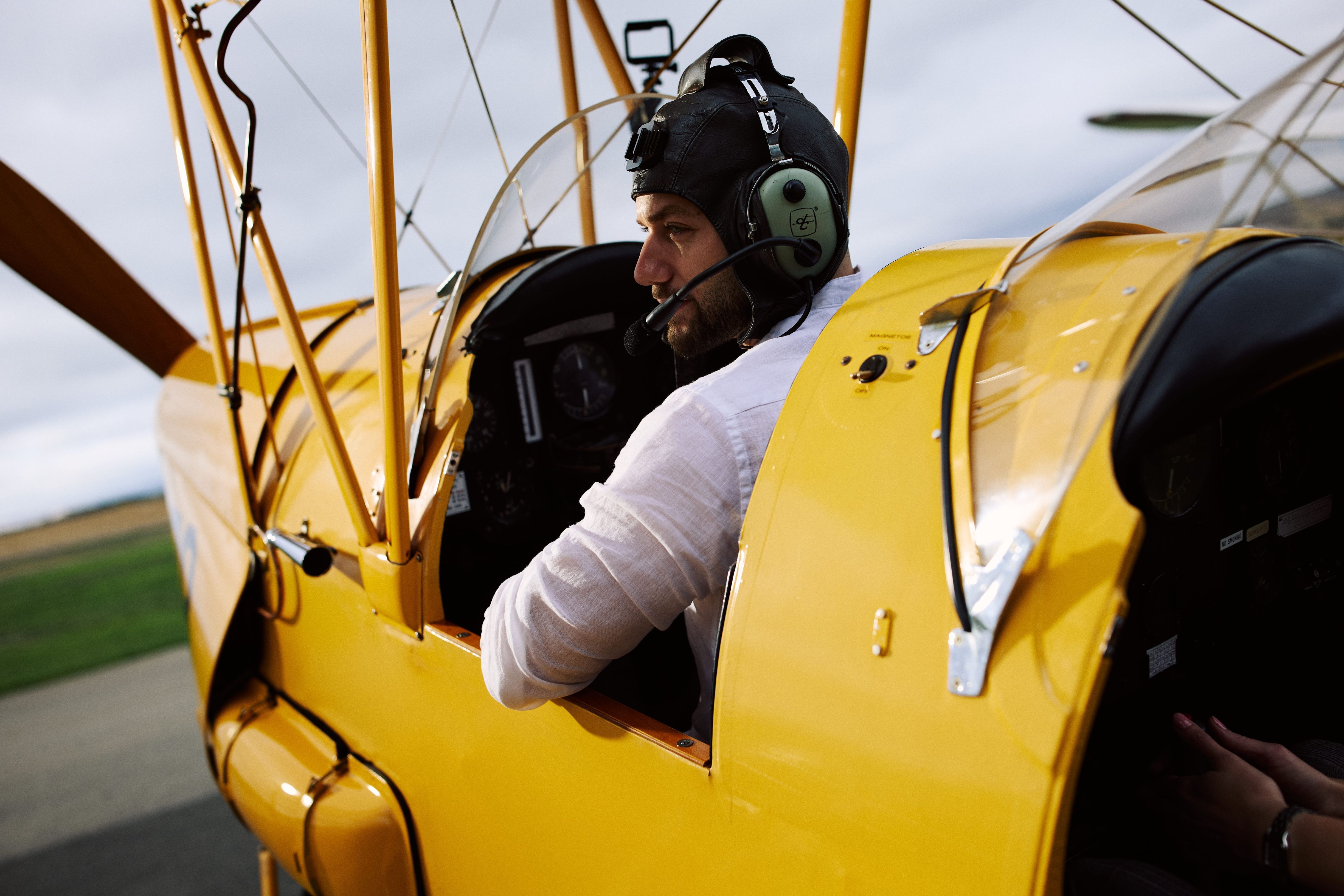 Man sitting in biplane with ear phones on flying the plane