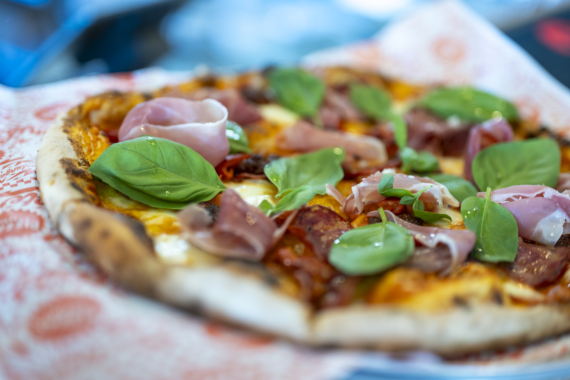 Pizza served on a platter with basil and salami