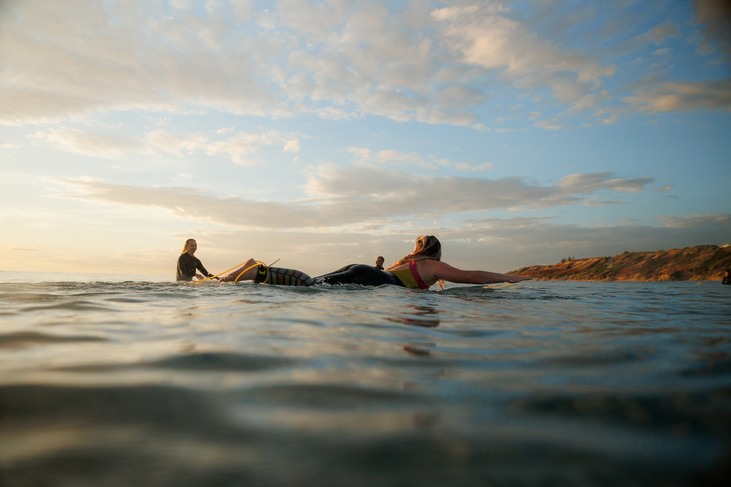 Two surfers paddling out on calm water at sunset along the Mid Coast, South Australia