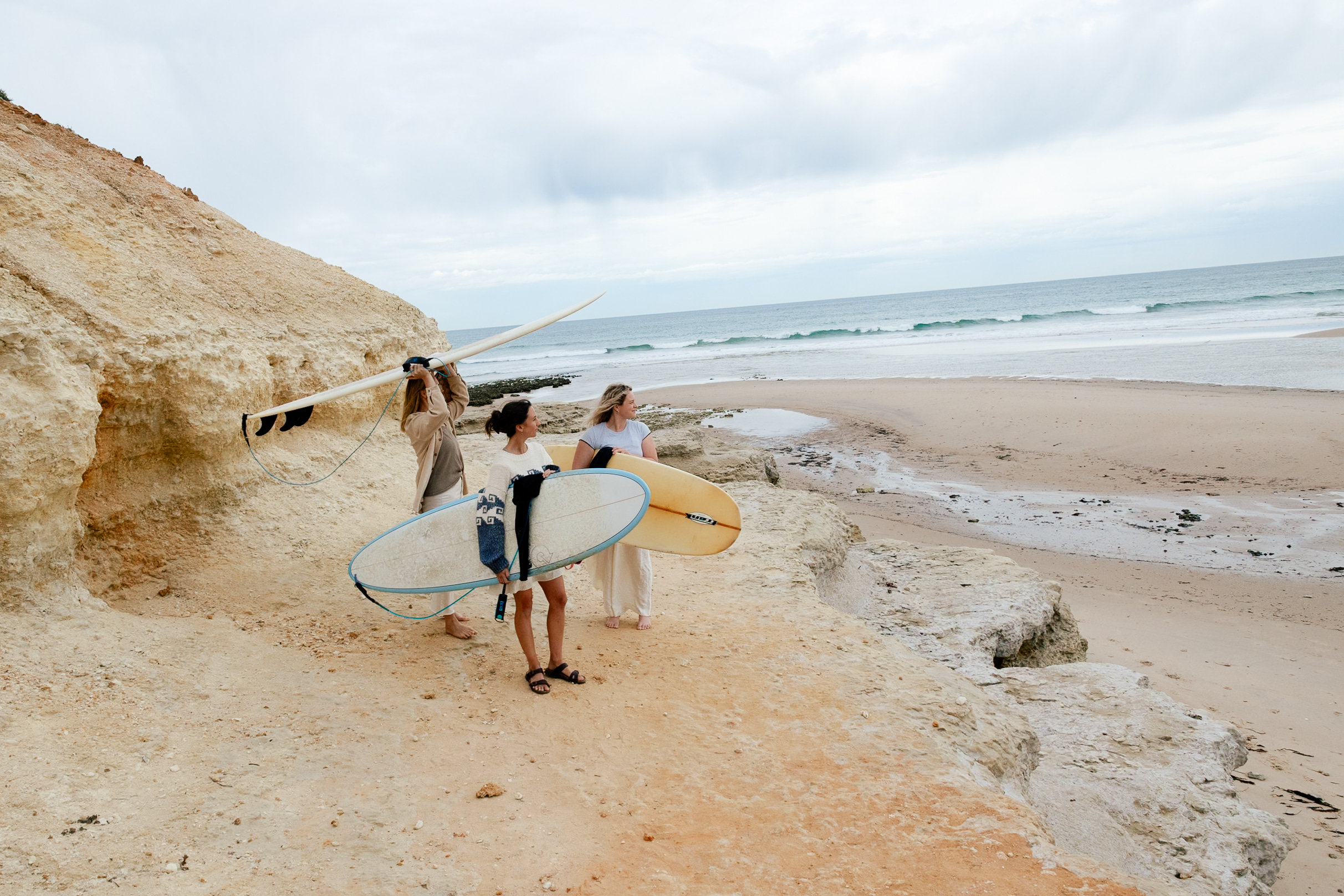 Surfers carrying boards across white sandy cliffs at Christies Beach, Mid Coast Surfing Reserve, South Australia