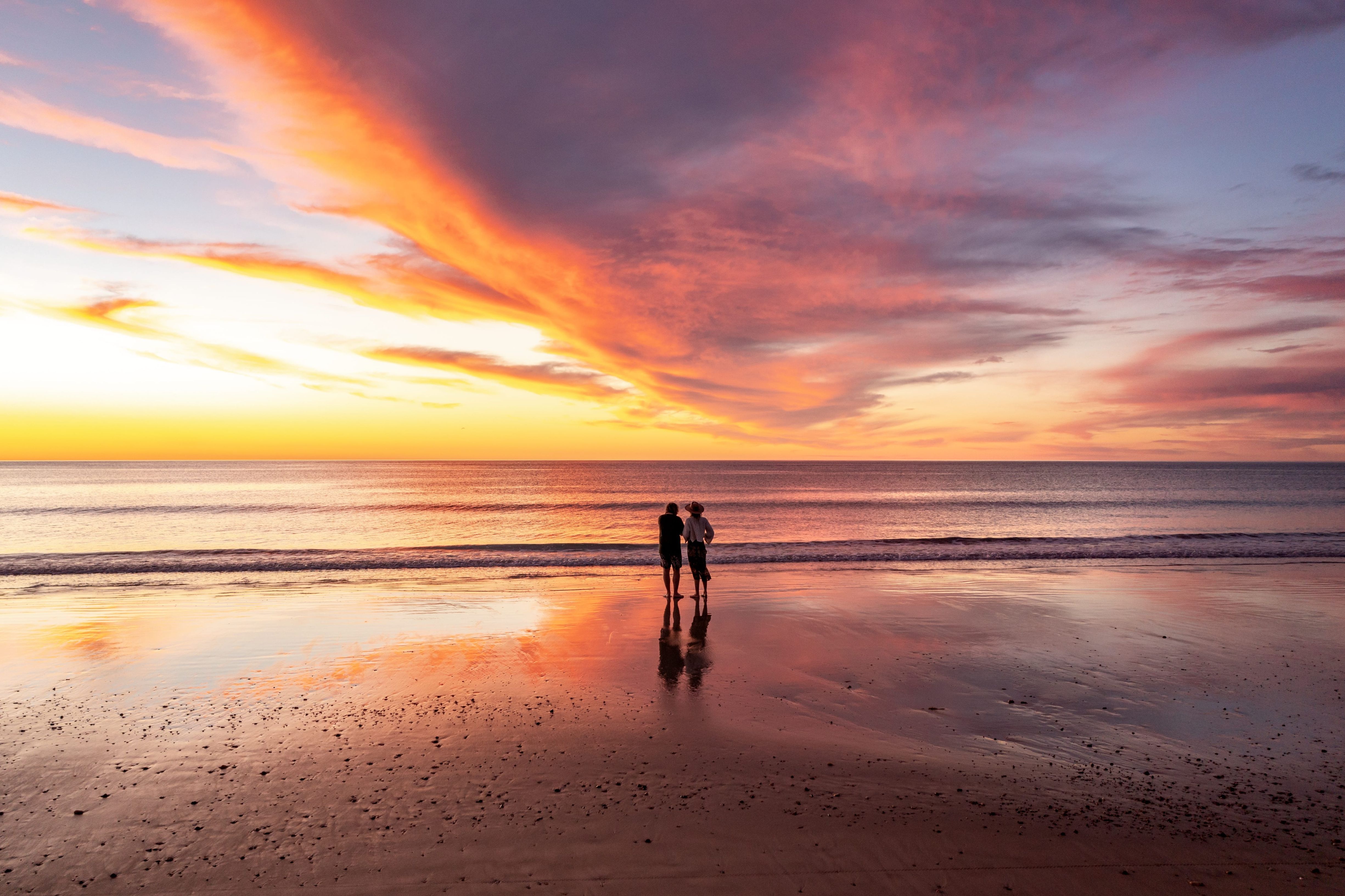 Two people standing on Port Willunga Beach looking at the golden sunset