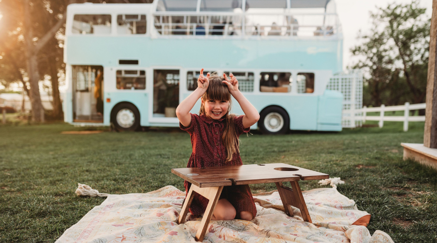 A young girl playing on the lawn in front of the iconic double-decker bus cellar door at Down the Rabbit Hole, McLaren Vale
